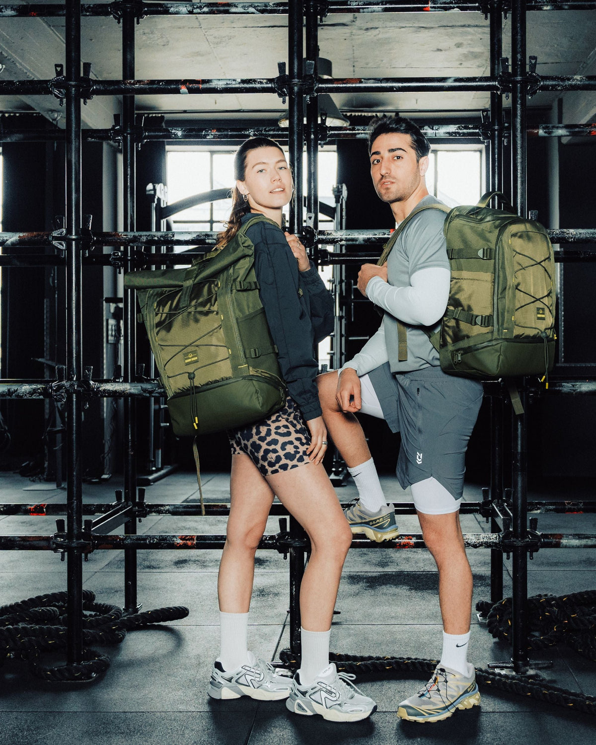 Frau und Mann in Sportkleidung mit olivgrünem Rolltop-Rucksack 'Allen Large Move' in einem Fitnessstudio