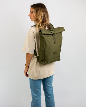 Frau trägt olivgrünen Rolltop Rucksack 'Robin Medium' von Johnny Urban, beige T-Shirt, blaue Jeans