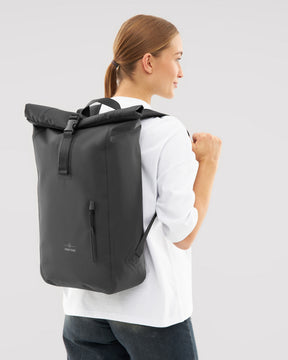Frau trägt schwarzen wasserfesten Rolltop Rucksack 'Conor' von Johnny Urban
