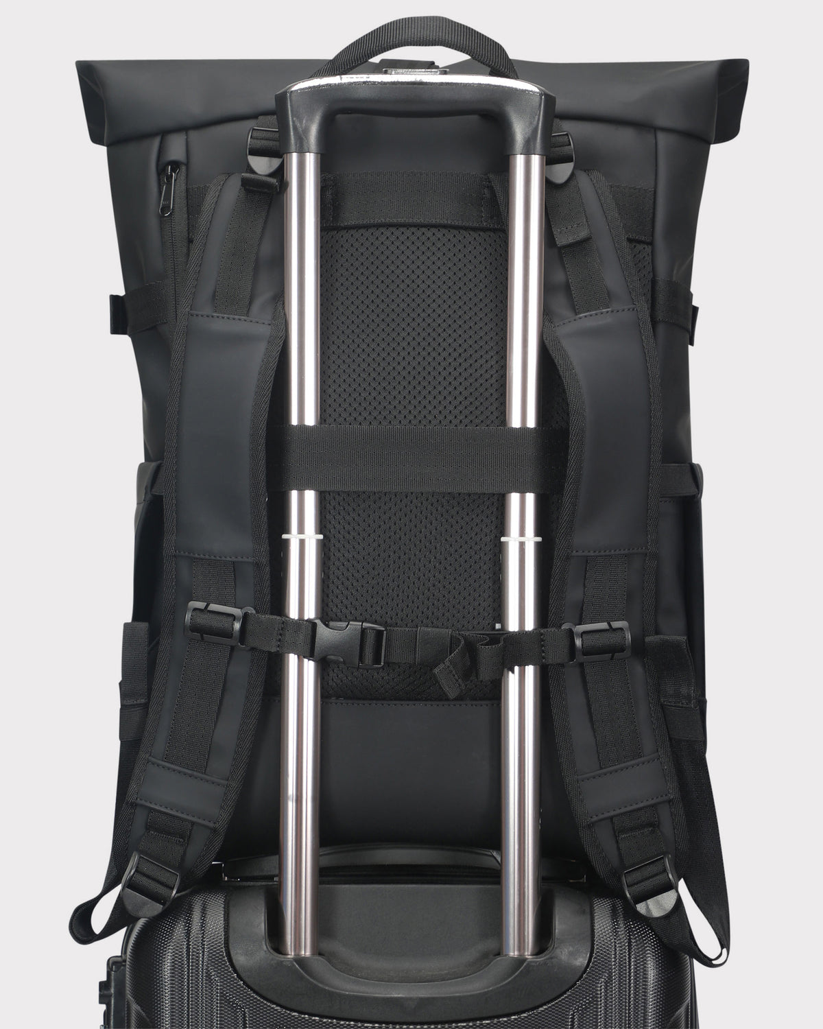 Schwarzer Rolltop Rucksack 'Harvey Large' mit Trageriemen um Teleskopgriff eines Rollkoffers befestigt