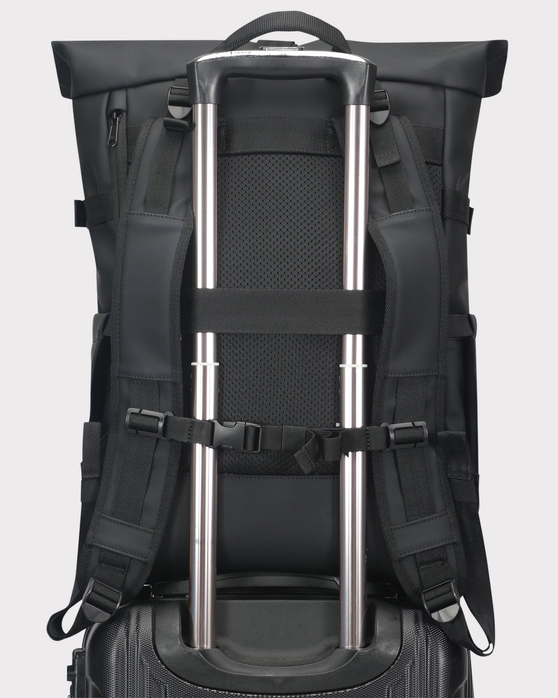 Schwarzer Rolltop Rucksack 'Harvey Large' mit Trageriemen um Teleskopgriff eines Rollkoffers befestigt