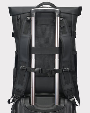 Schwarzer Rolltop Rucksack 'Harvey Large' mit Trageriemen um Teleskopgriff eines Rollkoffers befestigt