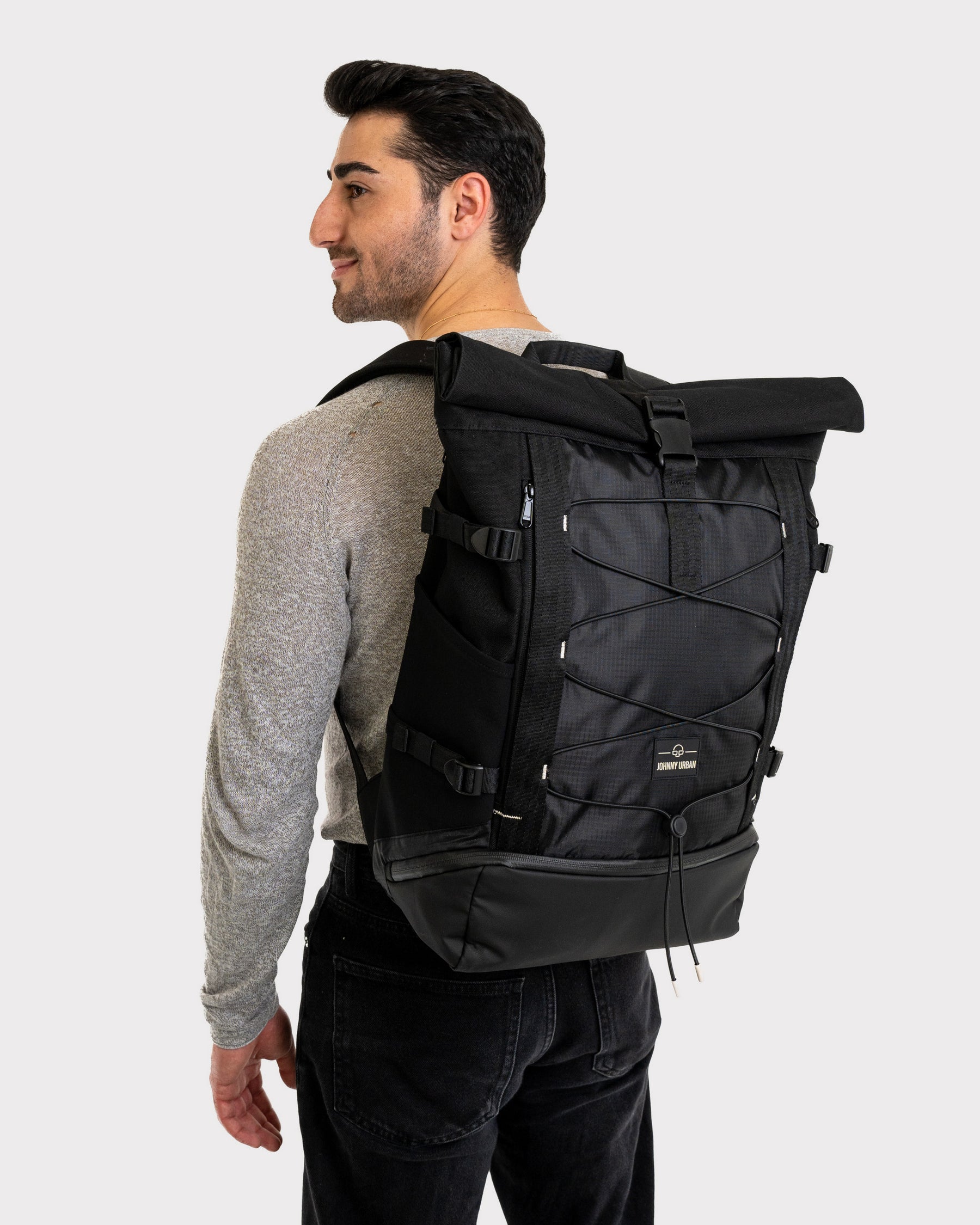 Mann mit grauem Pullover trägt schwarzen Rolltop Rucksack 'Allen Large Move' von Johnny Urban