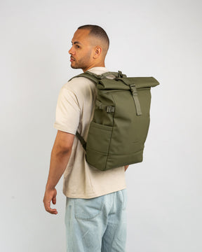 Mann trägt olivgrünen Rolltop Rucksack 'Harvey Large' von Johnny Urban, beige T-Shirt, helle Jeans