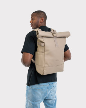 Beiger Rolltop-Rucksack 'Harvey Large' von Johnny Urban auf dem Rücken eines Mannes mit schwarzem T-Shirt und blauer Jeans