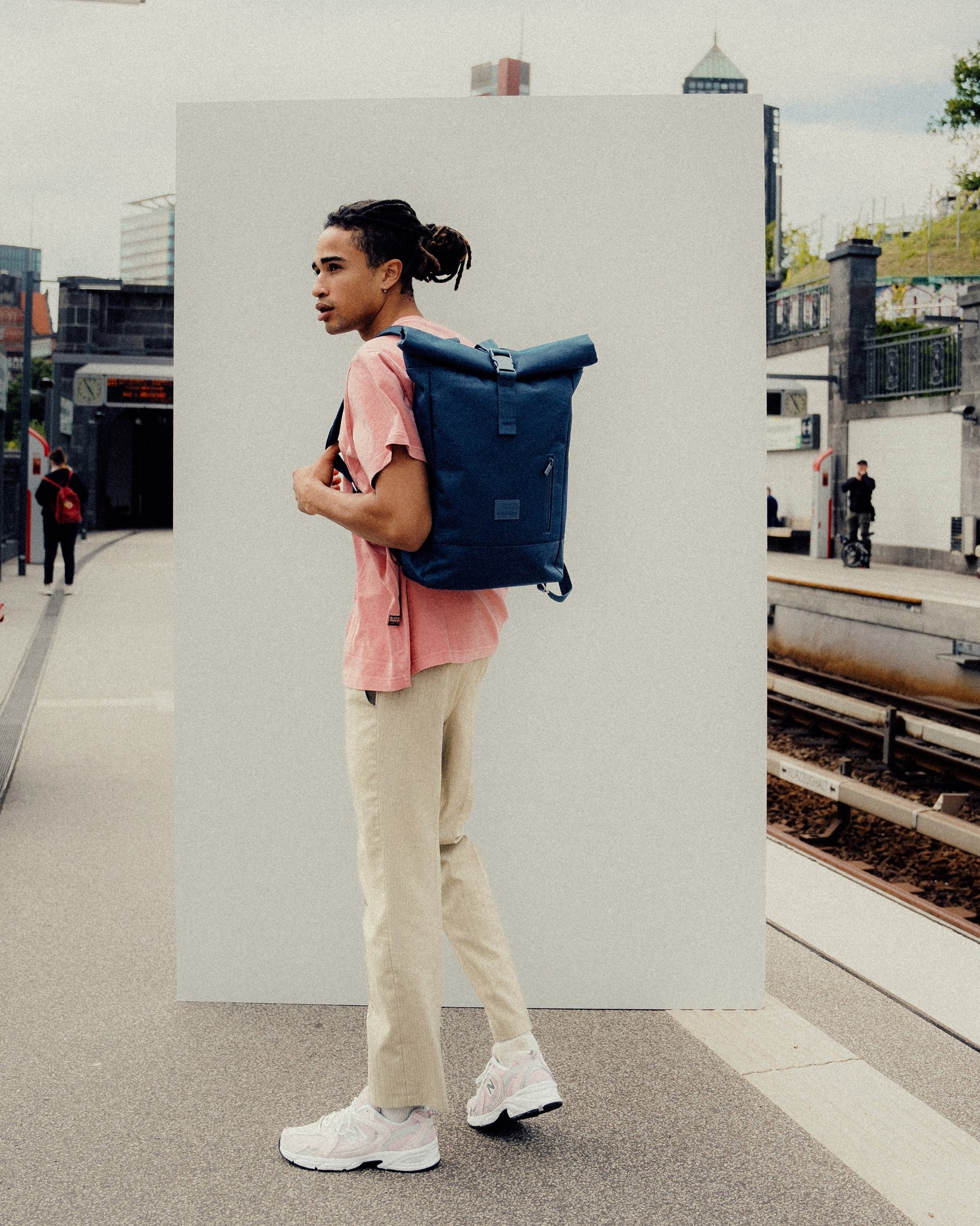 Mann mit blauem Johnny Urban Rolltop Rucksack 'Robin Medium' an einer U-Bahn-Station