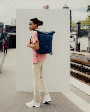 Mann mit blauem Johnny Urban Rolltop Rucksack 'Robin Medium' an einer U-Bahn-Station