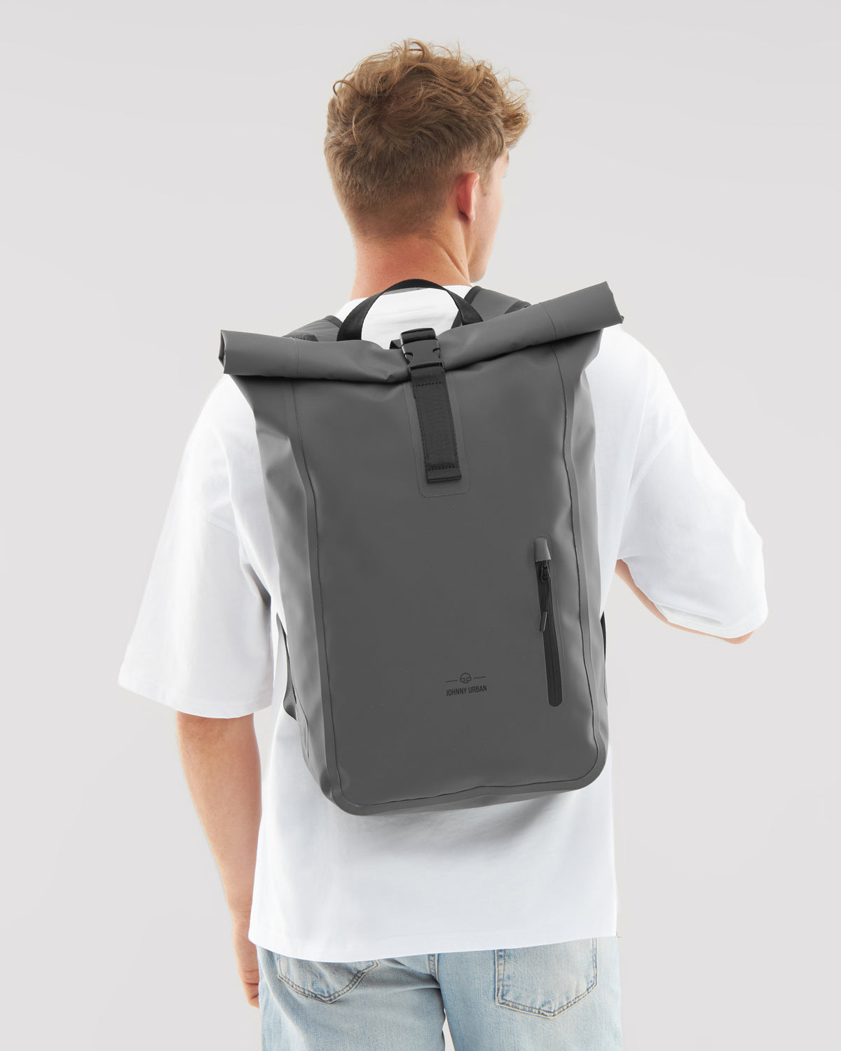 Mann mit weißem T-Shirt trägt grauen, wasserfesten Rolltop Rucksack 'Conor' von Johnny Urban