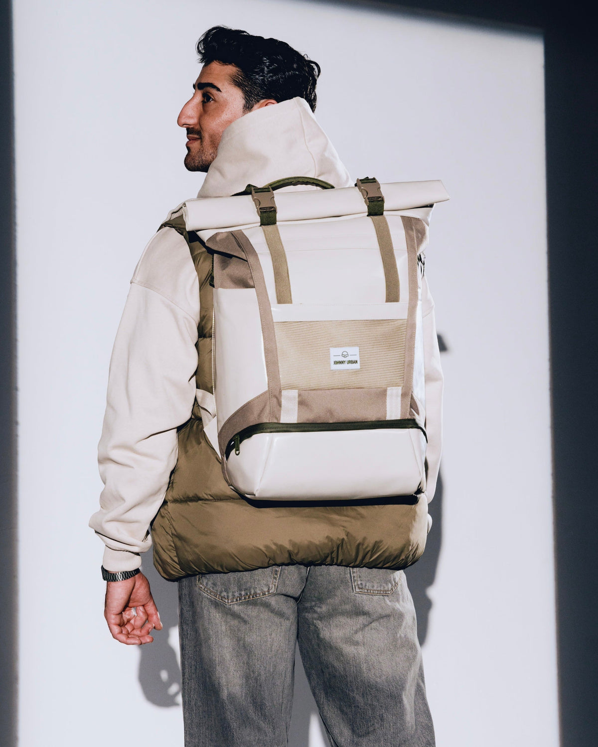 Mann trägt beigen Rolltop Rucksack 'Ashton' von Johnny Urban, dazu beige Jacke und graue Jeans