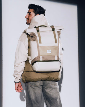 Mann trägt beigen Rolltop Rucksack 'Ashton' von Johnny Urban, dazu beige Jacke und graue Jeans