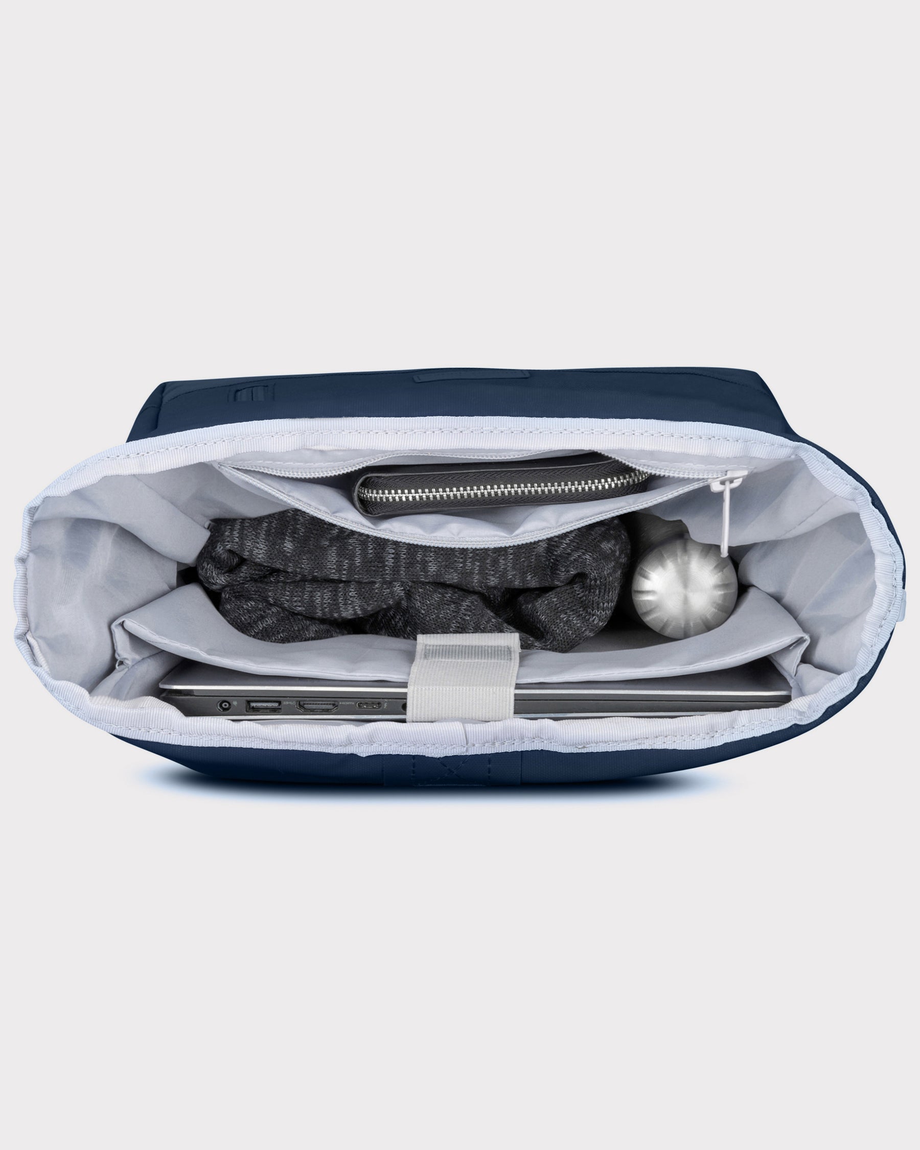 Blauer Rolltop Rucksack Johnny Urban 'Robin Medium' mit Laptop, grauem Pullover, Geldbeutel und Trinkflasche gefüllt
