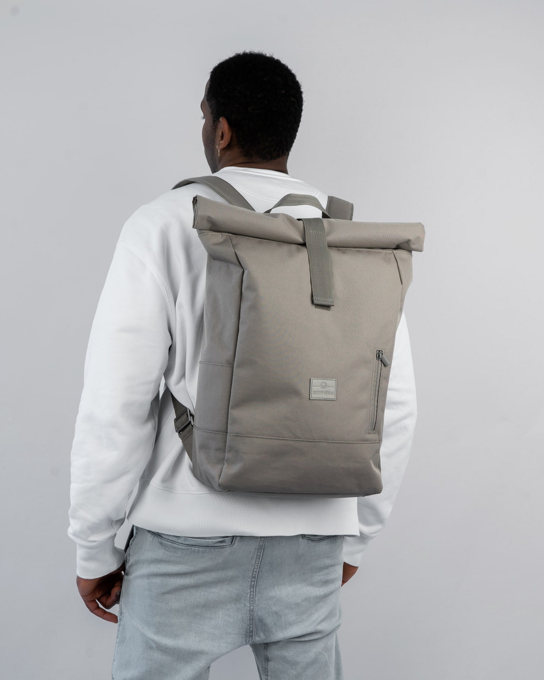 Mann trägt beigen Rolltop Rucksack 'Robin Large' von Johnny Urban mit Fronttasche und gepolsterten Schultergurten