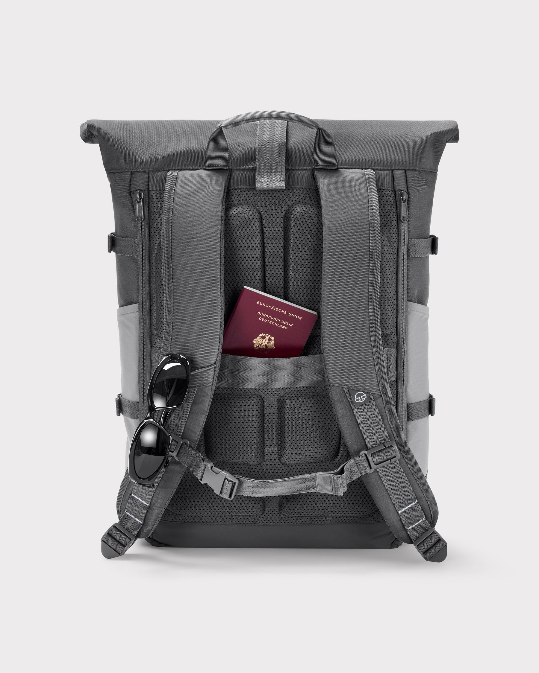 Rückseite des grauen Rolltop Rucksacks Allen Large Move mit gepolstertem Rücken, Brustgurt, verstecktem Reisepassfach und an Schulterriemen befestigten Sonnenbrillen
