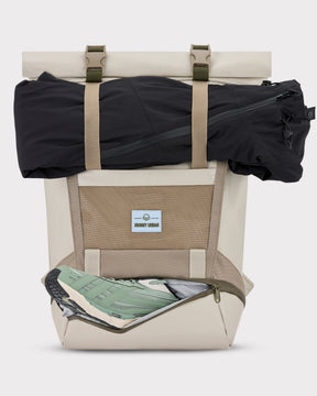 Rolltop-Rucksack 'Ashton' in Beige mit extra Schuhfach, grün-weißer Sneaker sichtbar, schwarze Kleidung oben befestigt