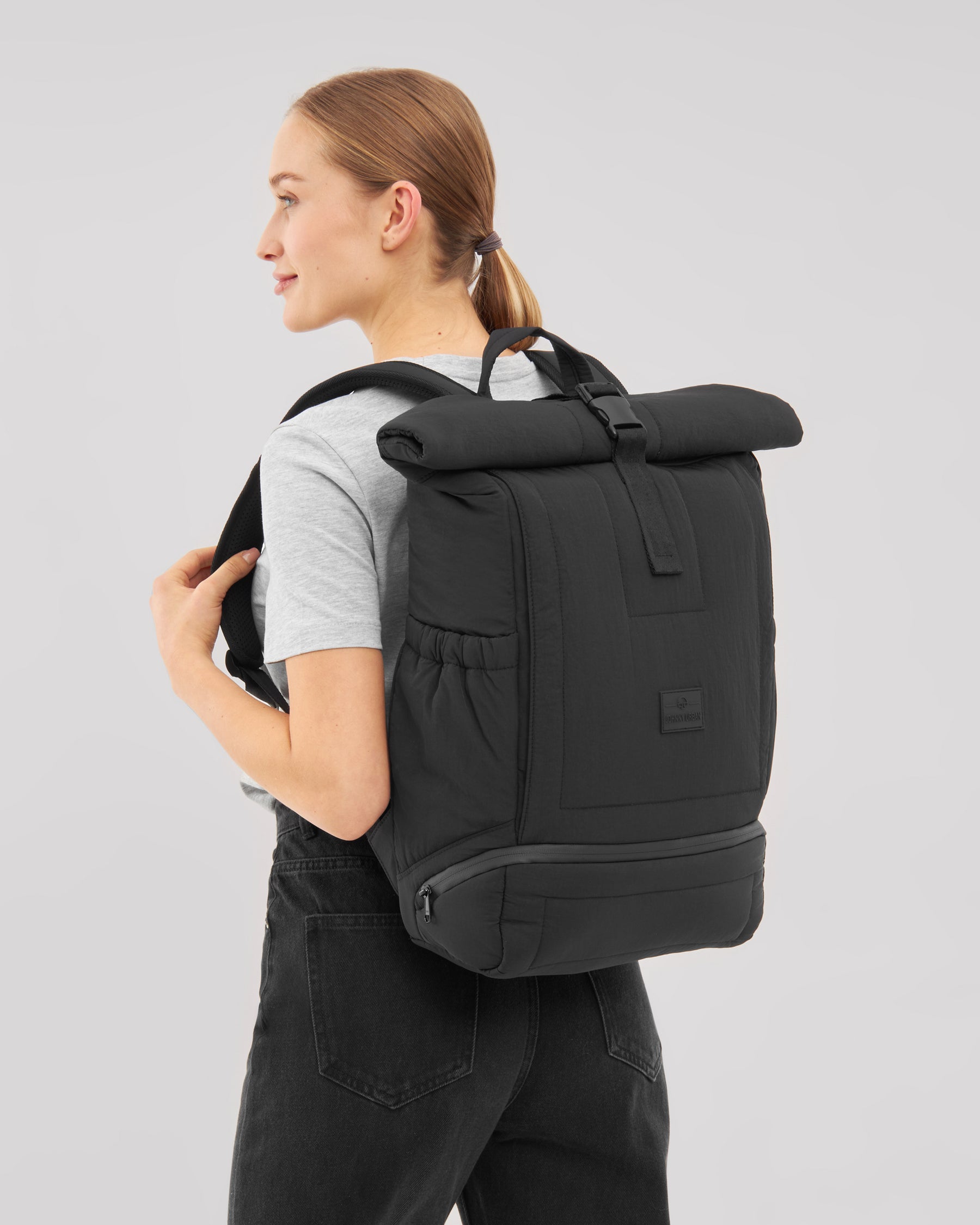 Frau trägt schwarzen gepolsterten Rolltop Rucksack ‚Kyle‘ von Johnny Urban mit seitlichen Taschen