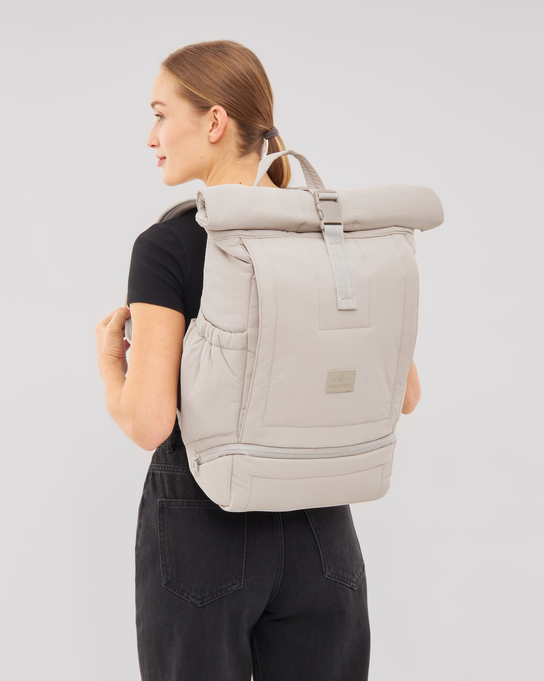 Beiger Rolltop Rucksack 'Kyle' von Johnny Urban an einer Frau mit schwarzem T-Shirt und schwarzer Hose