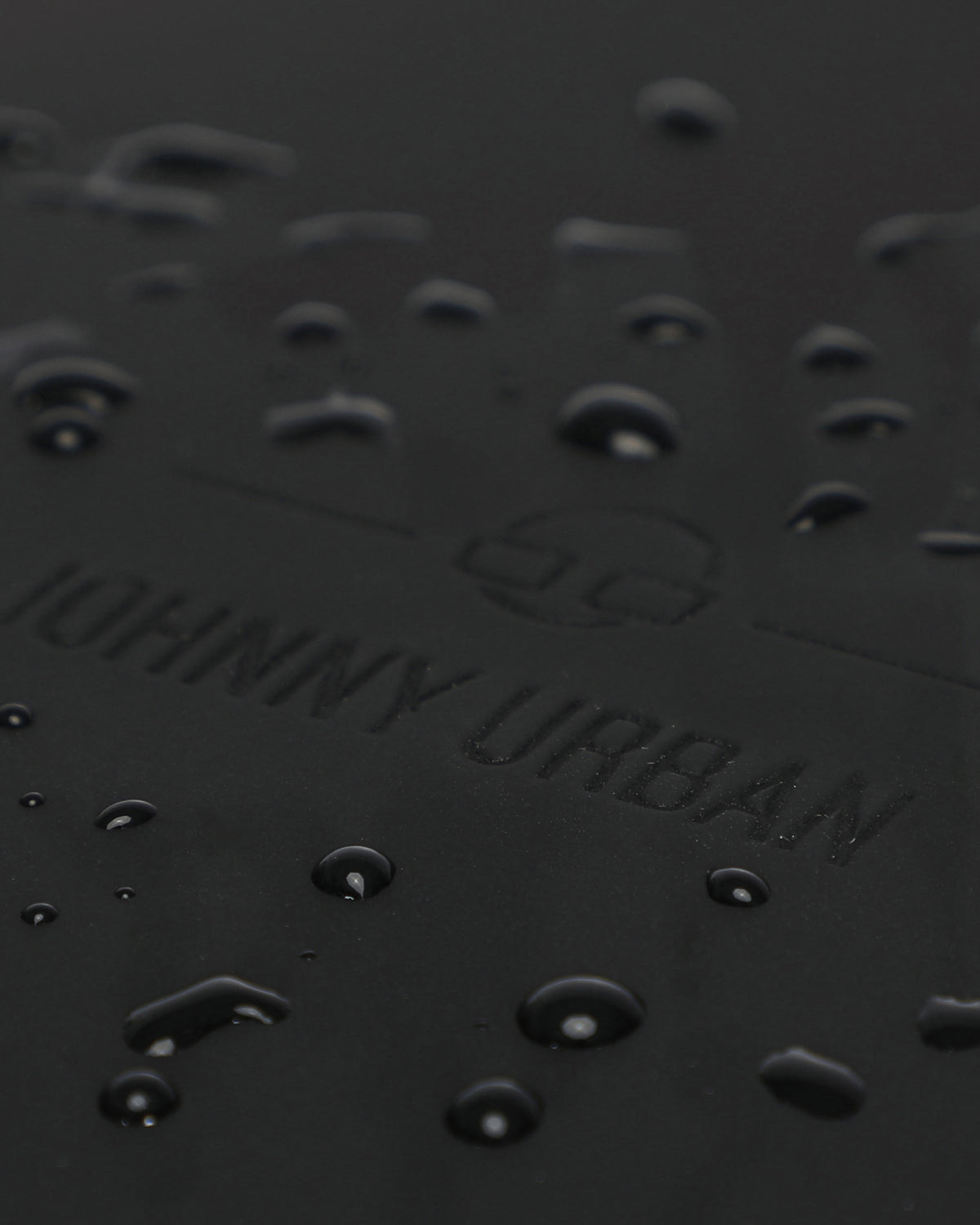 Wasserabweisende Oberfläche mit geprägtem Johnny Urban Logo auf schwarzem Material des Rolltop Rucksacks Harvey Large