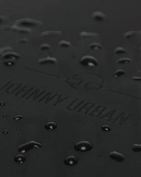 Wasserabweisende Oberfläche mit geprägtem Johnny Urban Logo auf schwarzem Material des Rolltop Rucksacks Harvey Large