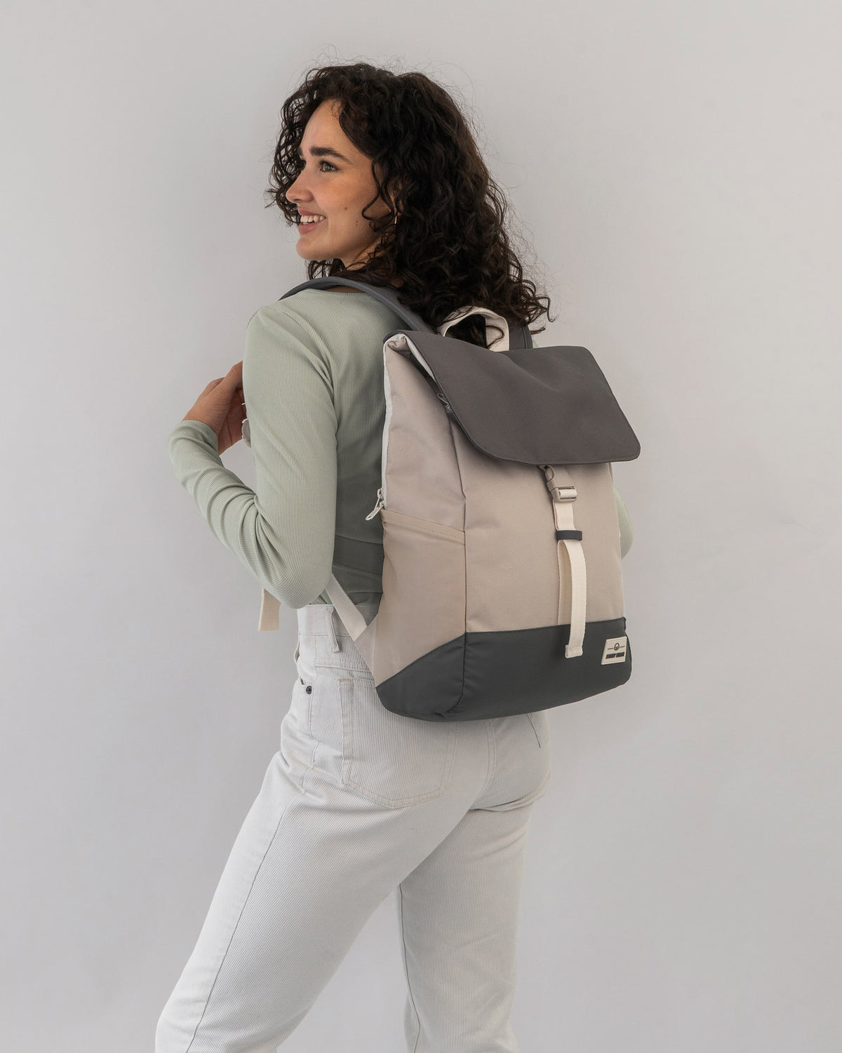 Frau trägt den beige-sandfarbigen Rucksack 'Mika' mit dunklem Deckel und Boden
