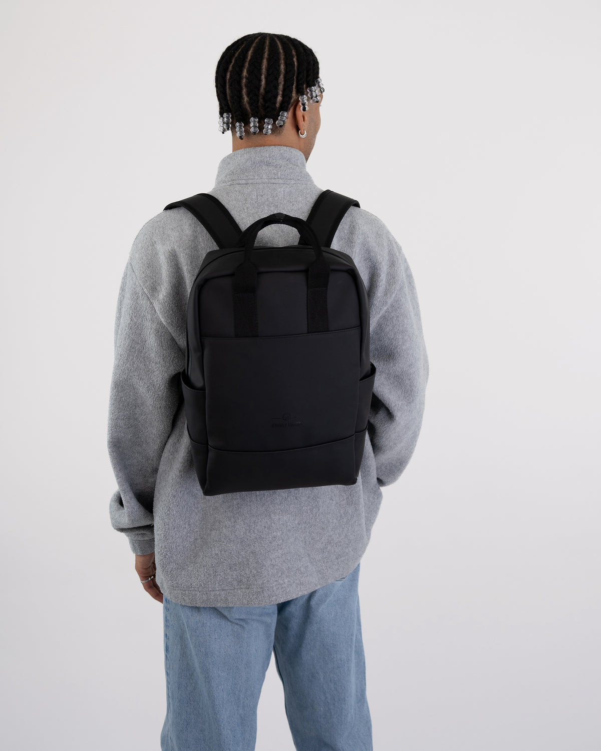 Schwarzer Rucksack 'Hailey' von Johnny Urban auf Rücken einer Person mit grauem Pullover und blauer Jeans