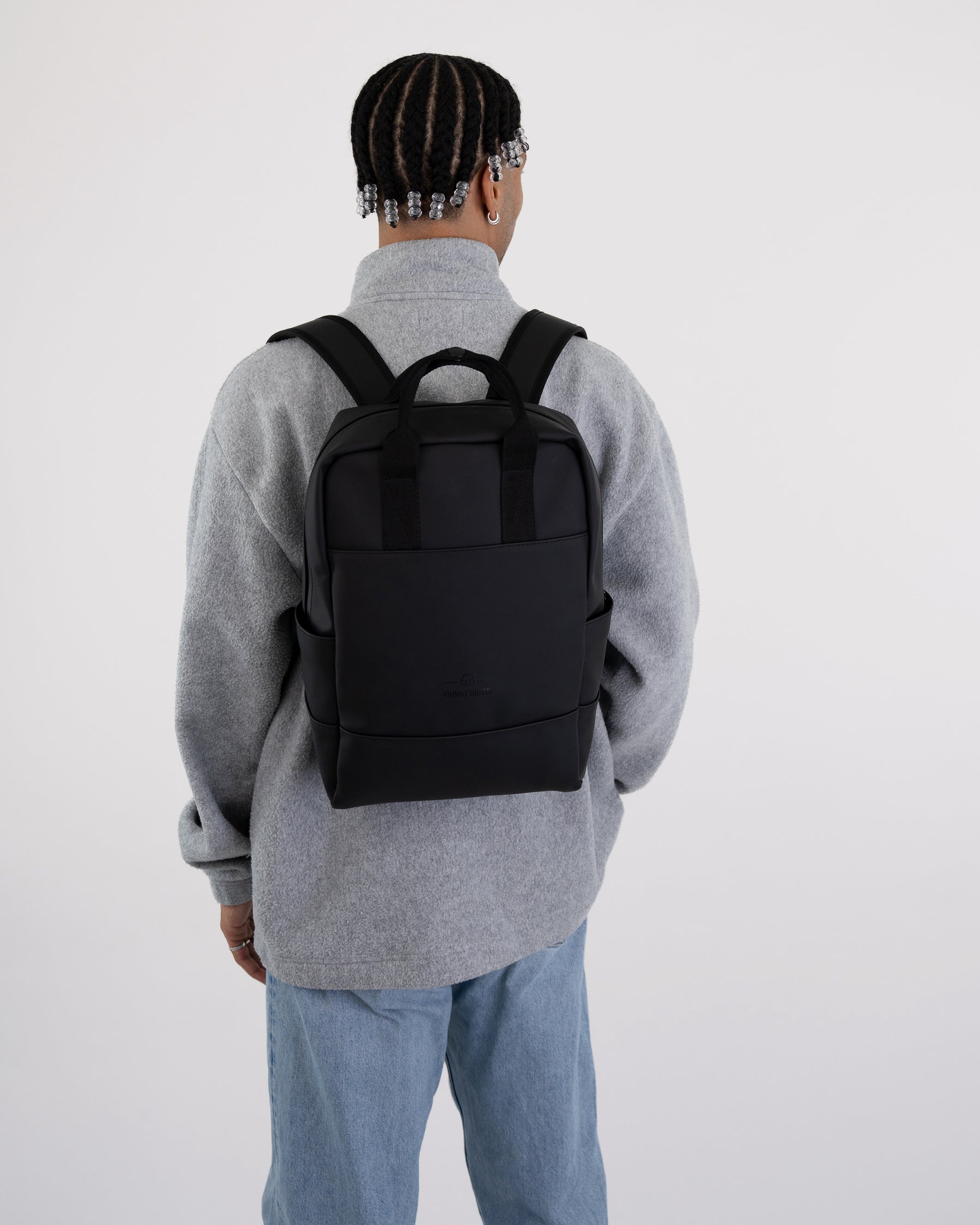 Schwarzer Rucksack 'Hailey' von Johnny Urban auf Rücken einer Person mit grauem Pullover und blauer Jeans
