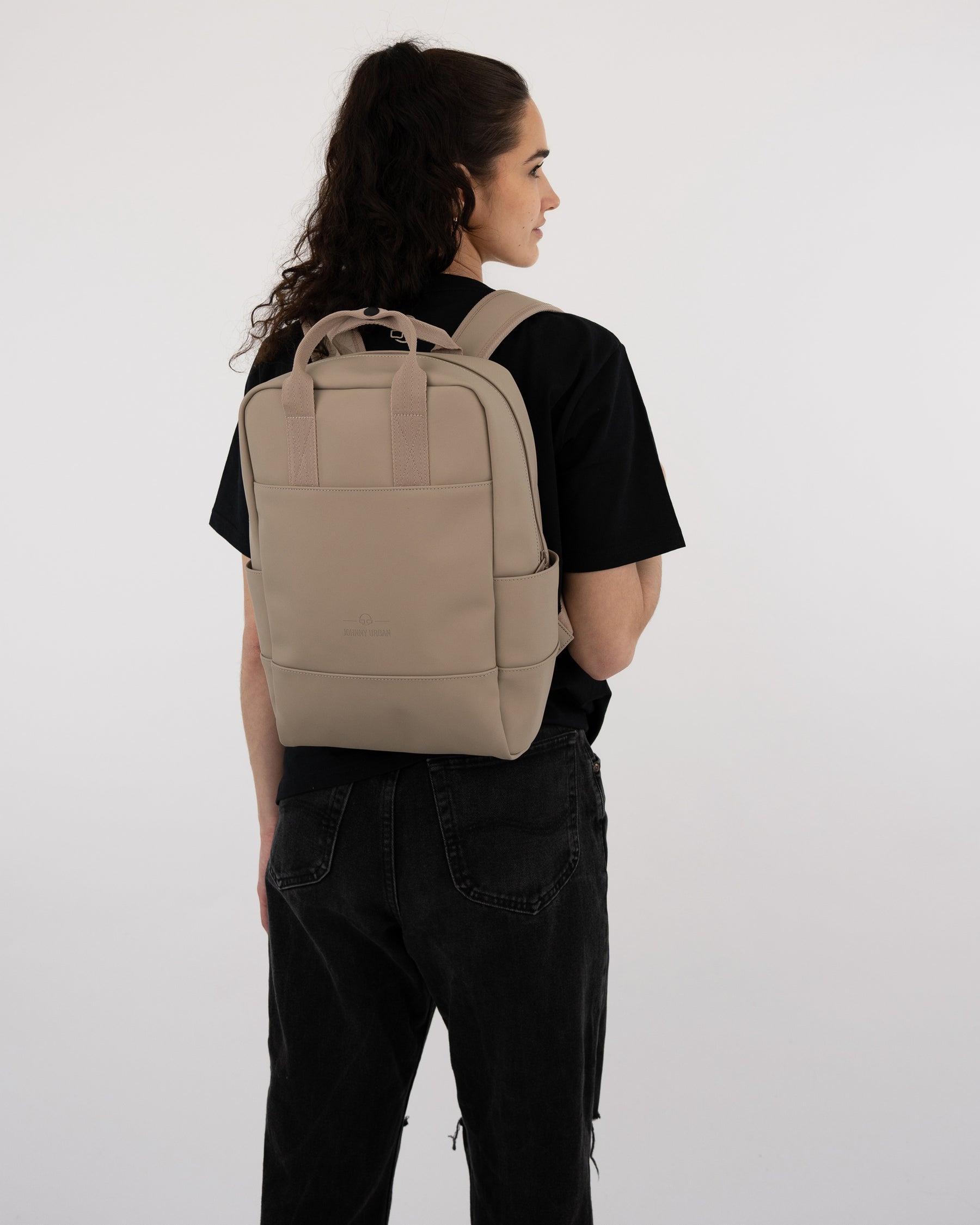 Beige Rucksack 'Hailey' von Johnny Urban getragen von Frau in schwarzem T-Shirt und schwarzen Jeans