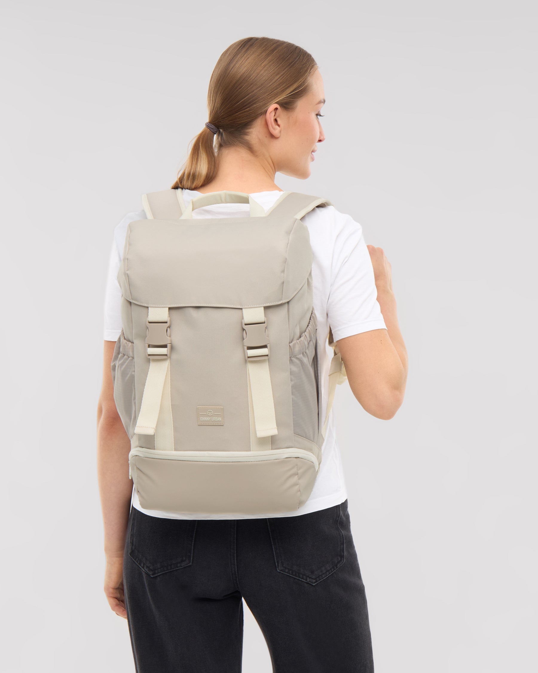 Frau von hinten mit sandfarbenem Rucksack 'Nico' von Johnny Urban, weißes T-Shirt, schwarze Hose