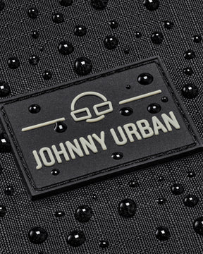 Nahe Aufnahme des Johnny Urban Logos auf einem wasserabweisenden schwarzen Gewebe mit Wassertropfen