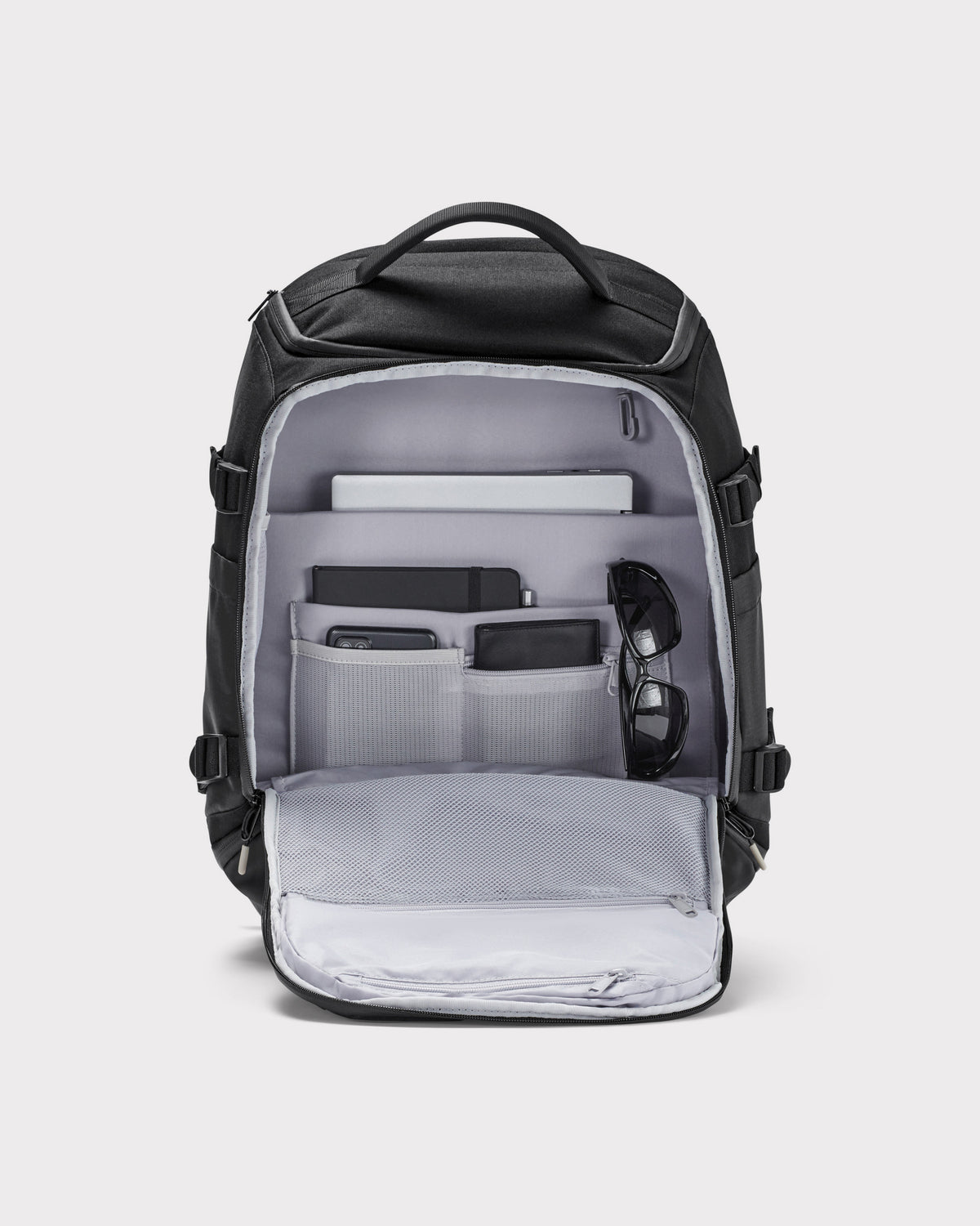 Schwarzer Rucksack 'Jack' von Johnny Urban mit mehreren Fächern, geöffnet und bestückt mit Notebook, Notizbuch, Smartphone, Geldbörse und Sonnenbrille