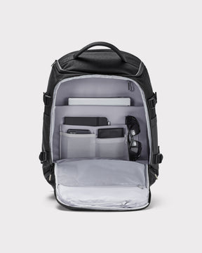 Schwarzer Rucksack 'Jack' von Johnny Urban mit mehreren Fächern, geöffnet und bestückt mit Notebook, Notizbuch, Smartphone, Geldbörse und Sonnenbrille