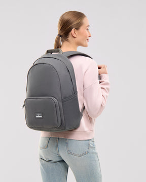 Frau trägt dunkelgrauen Rucksack 'Mo' von Johnny Urban, rosa Pullover, blaue Jeans