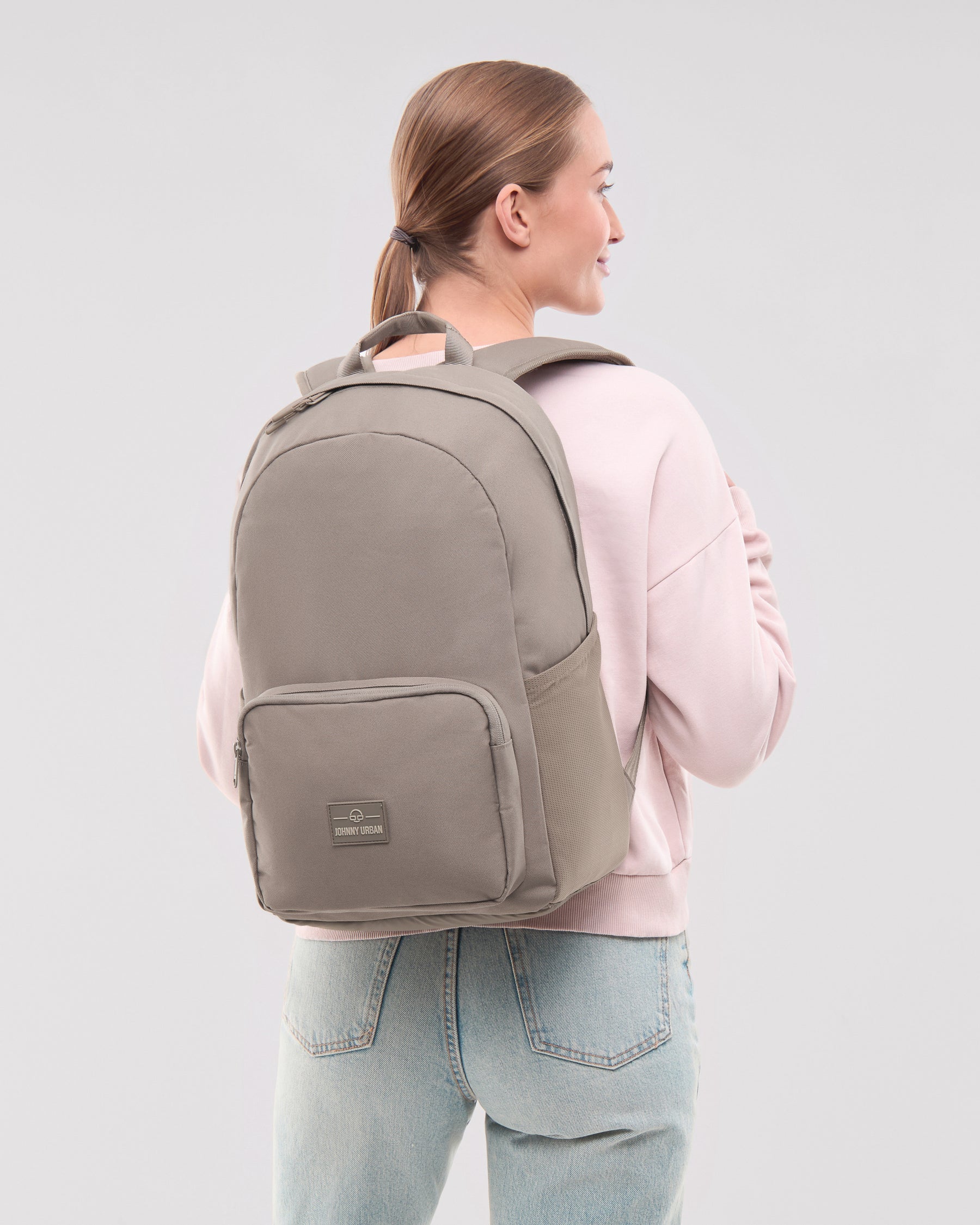 Frau mit Zopf trägt den Johnny Urban Rucksack 'Mo' in desert grey, seitlich gesehen