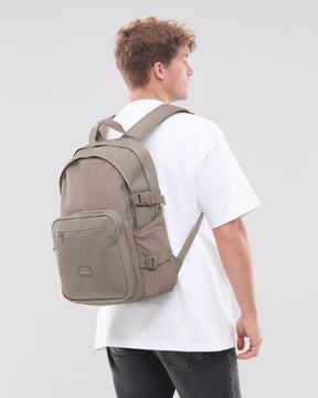 Herren trägt Rucksack 'Lian' in desert-grau auf weißem T-Shirt und schwarzen Jeans