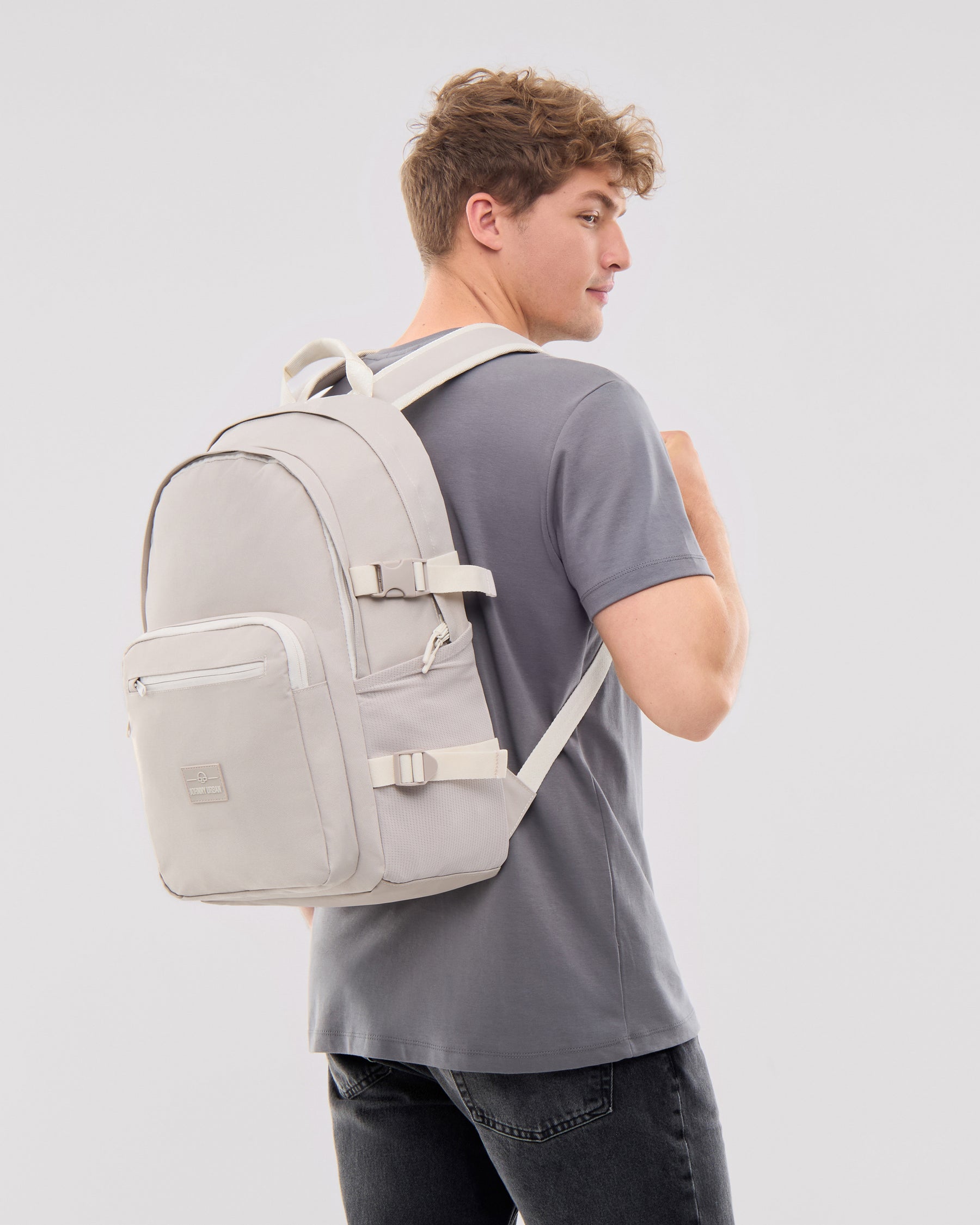 Sandfarbener Rucksack 'Lian' mit mehreren Fächern und verstellbaren Riemen auf Rücken eines Mannes mit grauem T-Shirt
