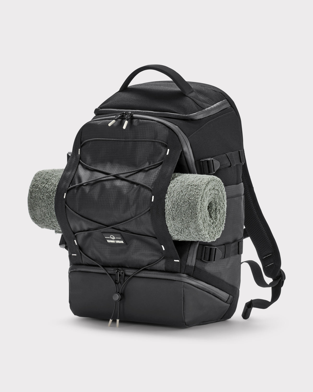 Schwarzer Johnny Urban Rucksack 'Jack' aus robustem Material mit aufgerolltem grauen Handtuch an der Außenseite