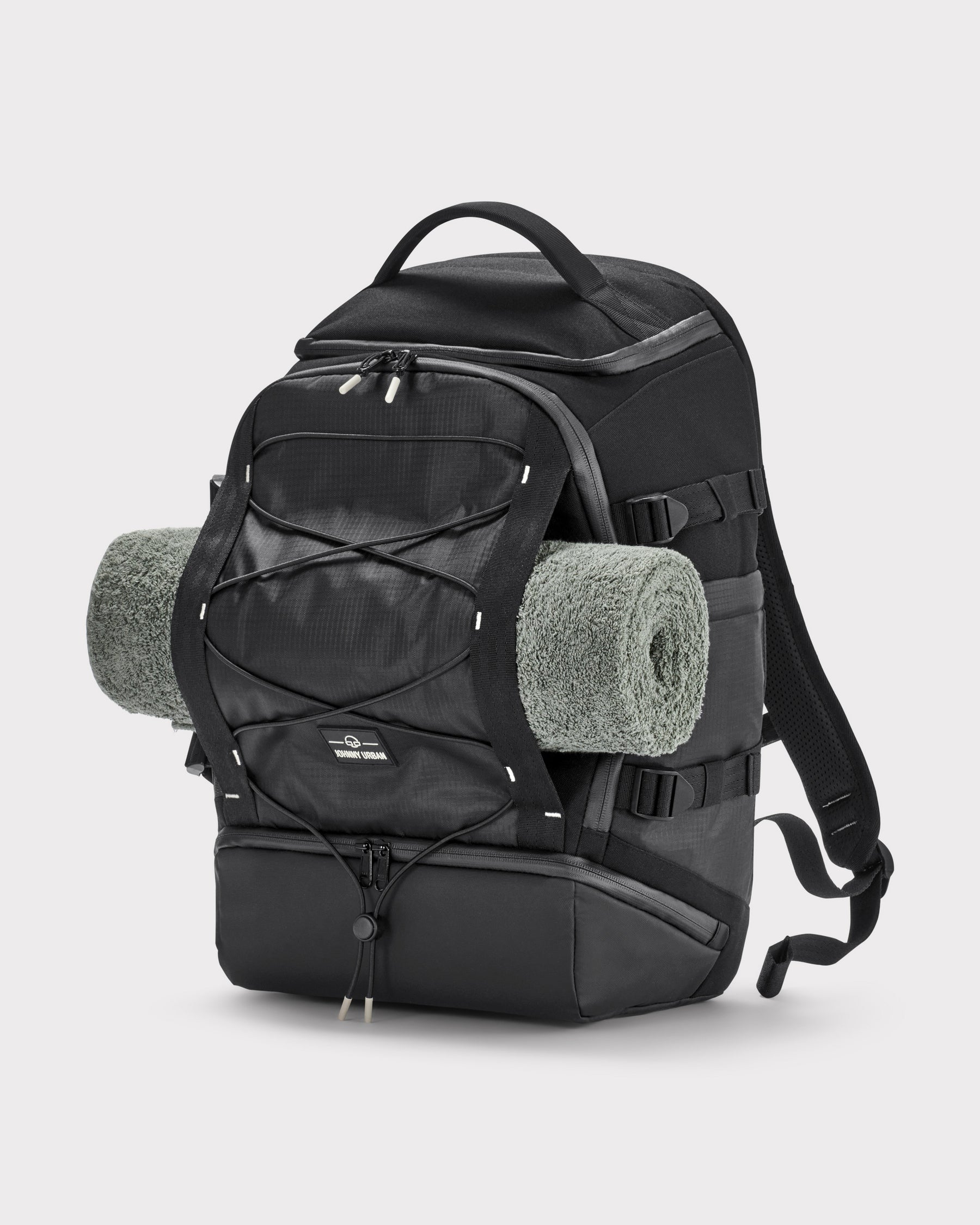 Schwarzer Johnny Urban Rucksack 'Jack' aus robustem Material mit aufgerolltem grauen Handtuch an der Außenseite