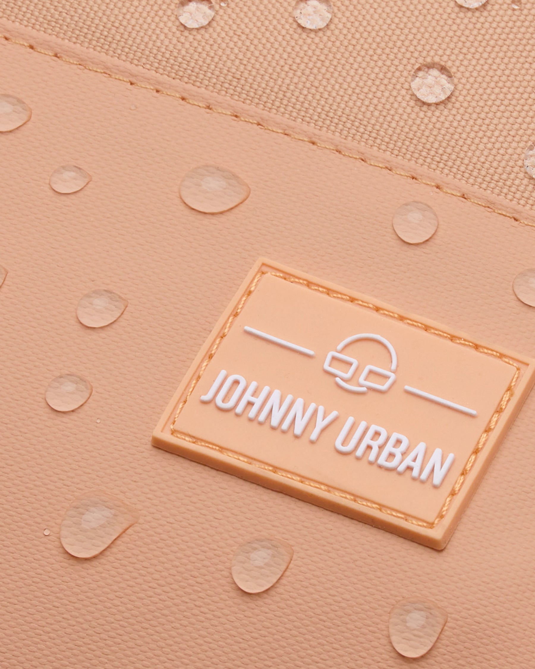 Nahaufnahme des wasserabweisenden Stoffes des Johnny Urban Rucksacks 'Mika' in Pfirsich mit Wassertröpfchen