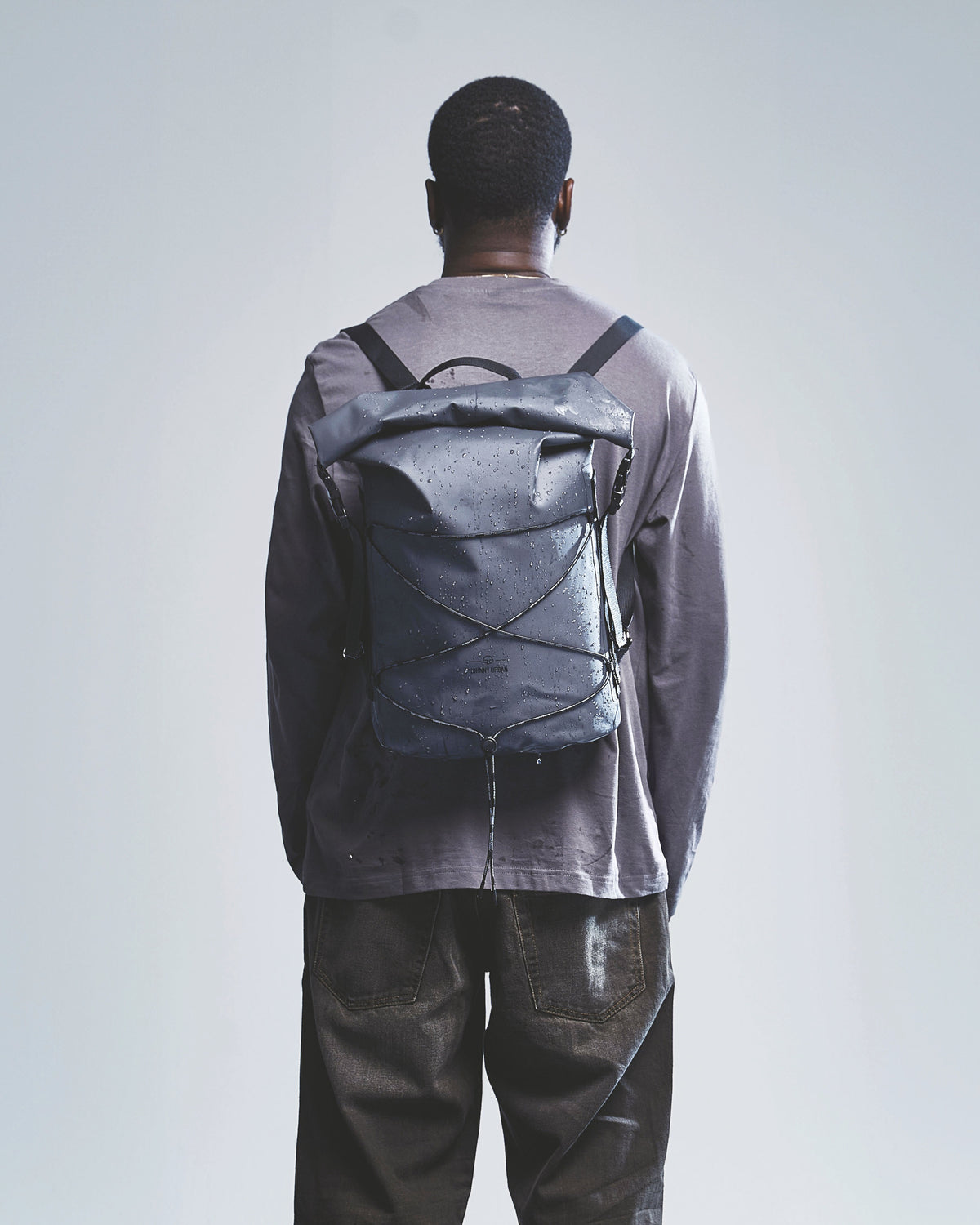 Mann mit wasserabweisendem schwarzen Rolltop Rucksack 'Myles' von Johnny Urban von hinten