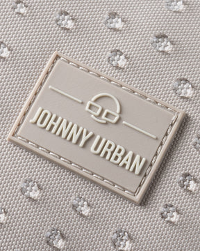 Nahaufnahme des wasserfesten sandfarbenen Rucksacks 'Mo' mit Johnny Urban Logo in einer rechteckigen Gummimarke