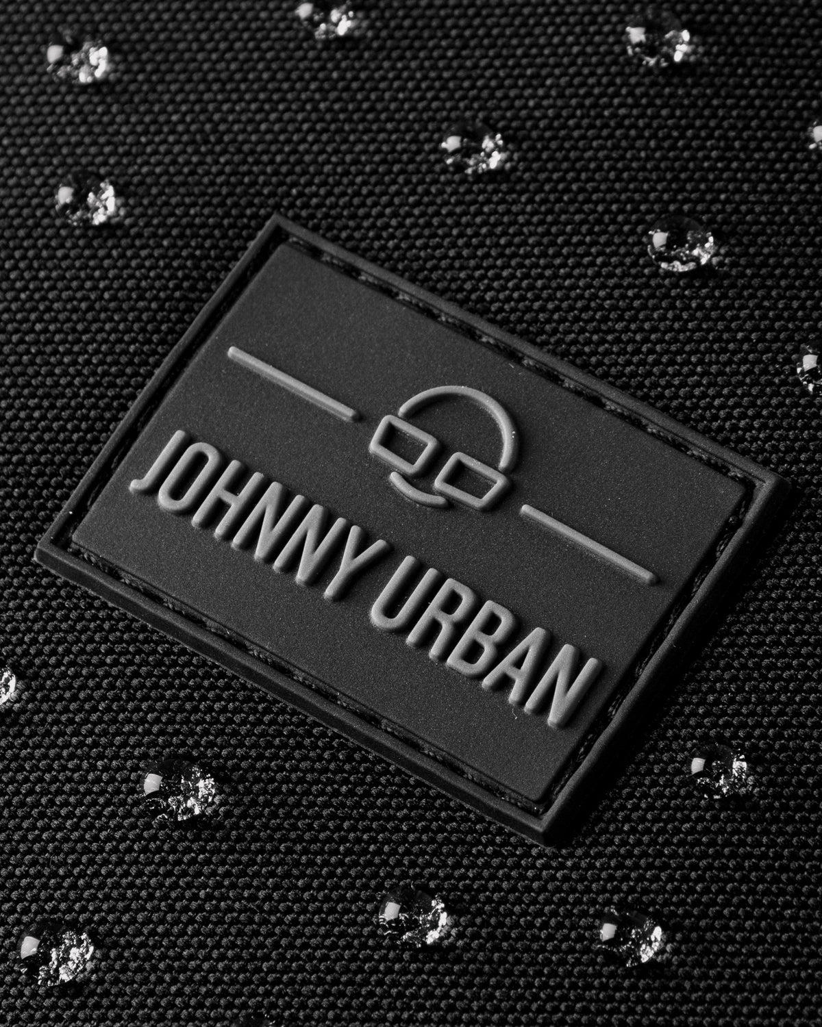 Schwarze Johnny Urban Markierung auf wasserfestem Rucksackgewebe mit Wassertropfen