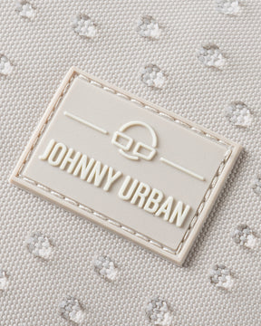 Nahaufnahme des Johnny Urban Logos auf sandfarbenem, wasserdichtem Rucksackstoff mit gepunkteter Struktur