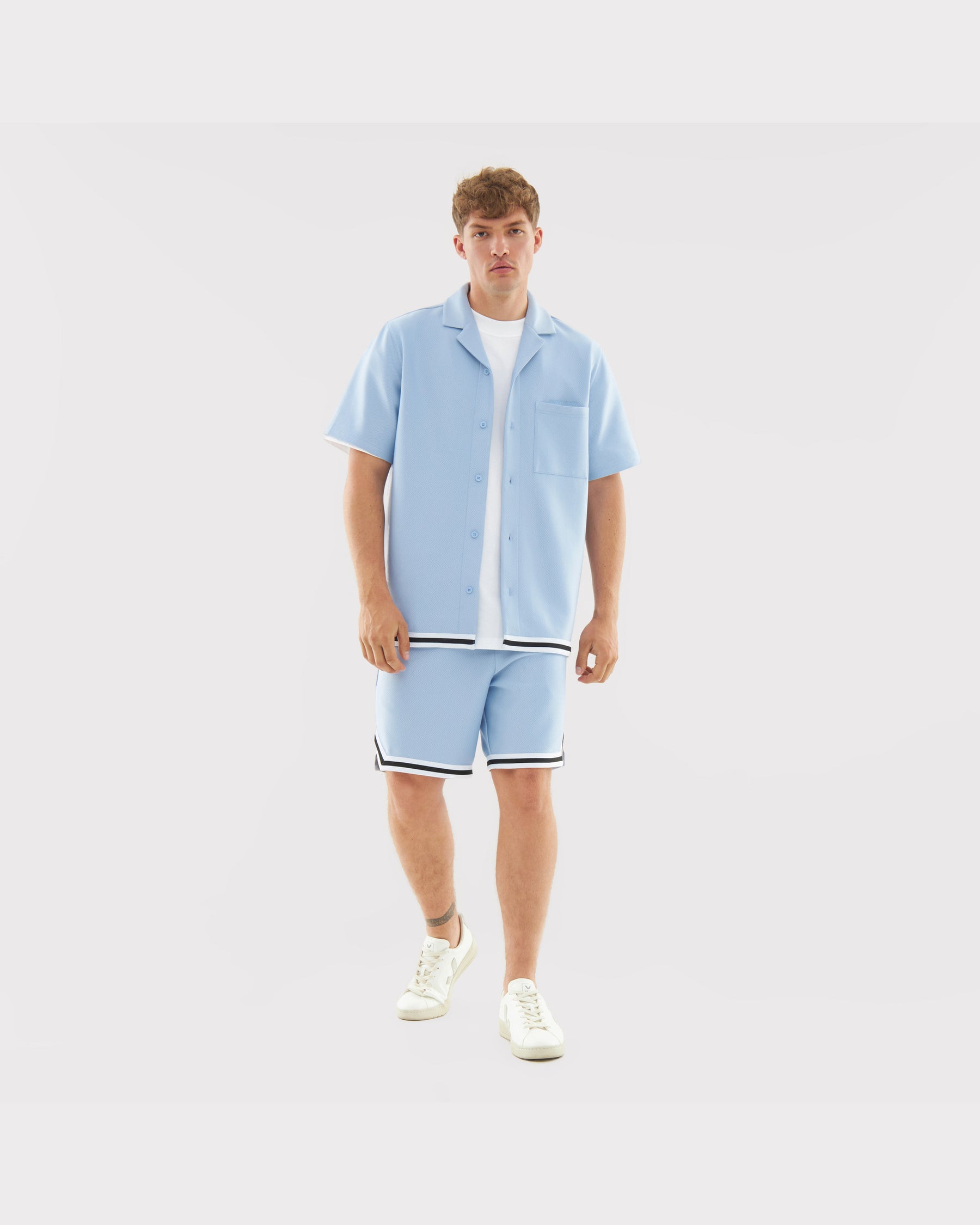 Mann in hellblauem Sommerhemd und Shorts mit schwarzen und weißen Streifen, Teil des Sets 'Parker'