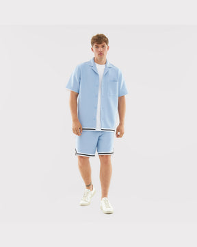 Mann in hellblauem Sommerhemd und Shorts mit schwarzen und weißen Streifen, Teil des Sets 'Parker'