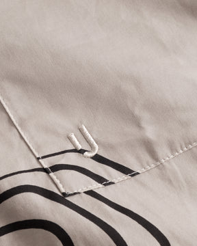 Sandfarbene Baumwolltasche mit schwarzem, abstraktem Linienmuster und gesticktem 'JU'-Logo