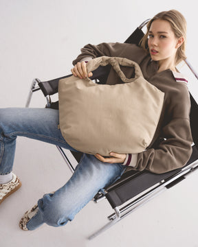 Unser weibliches Model präsentiert hier die Shopper-Tote-Bag "Cleo" in beige. 