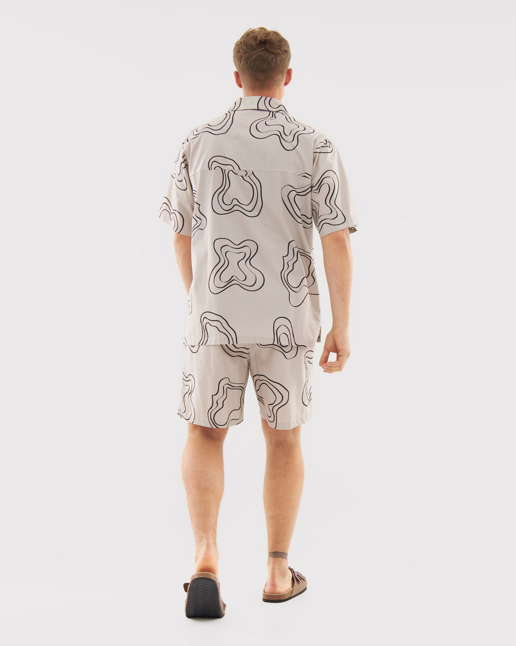 Mann von hinten trägt sandfarbene Shorts 'Spencer' mit schwarzem abstraktem Muster und passenden kurzärmligen Hemd