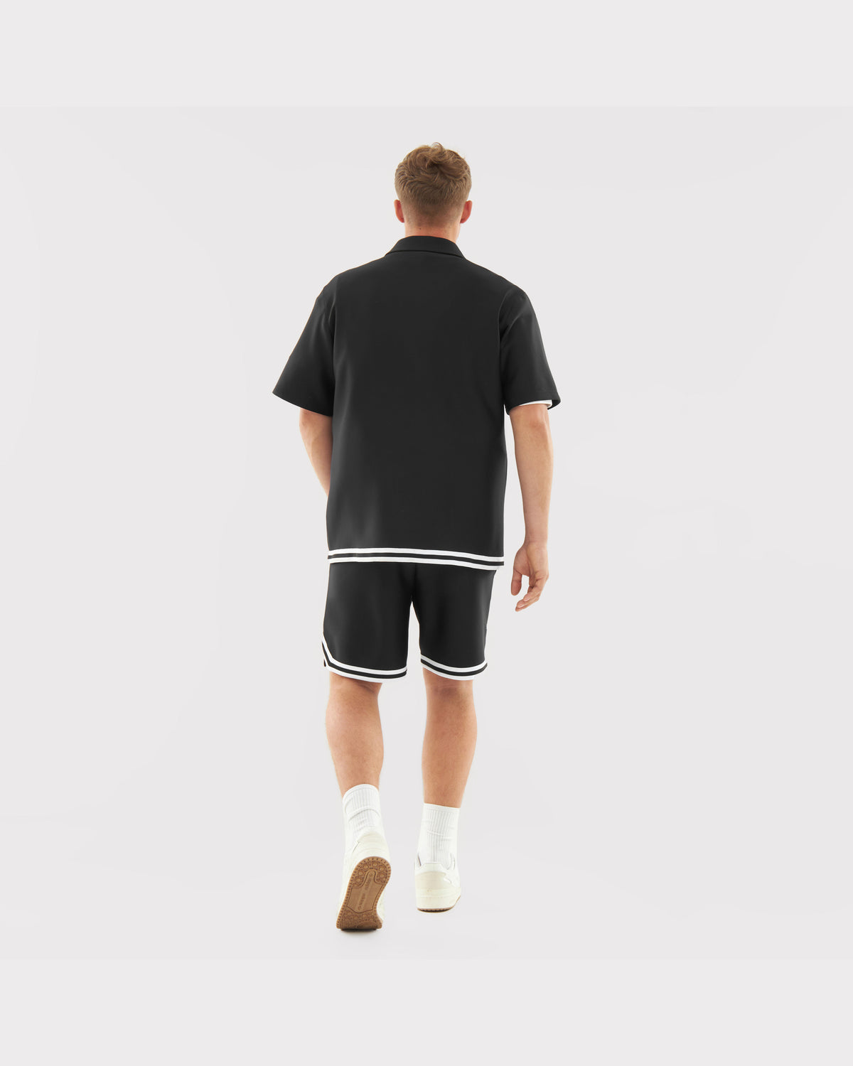 Mann von hinten trägt schwarze Shorts 'Parker' mit weißem Saum und schwarzes Kurzarmhemd