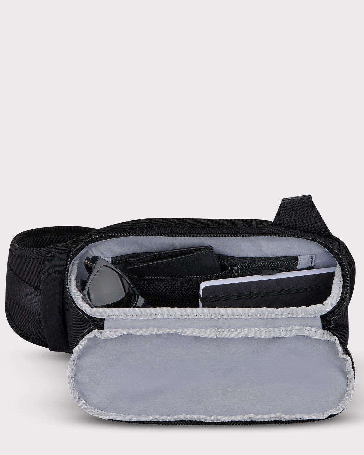 Johnny Urban Sling Bag 'Charlie' in Schwarz, geöffneter Innenraum mit Sonnenbrille, Geldbörse und Tablet