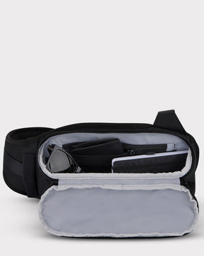 Johnny Urban Sling Bag 'Charlie' in Schwarz, geöffneter Innenraum mit Sonnenbrille, Geldbörse und Tablet