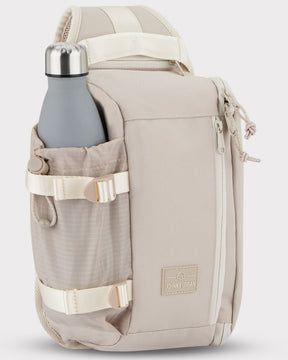 Beiger Johnny Urban Sling Bag 'Charlie' mit seitlicher Tasche und grauer Trinkflasche.
